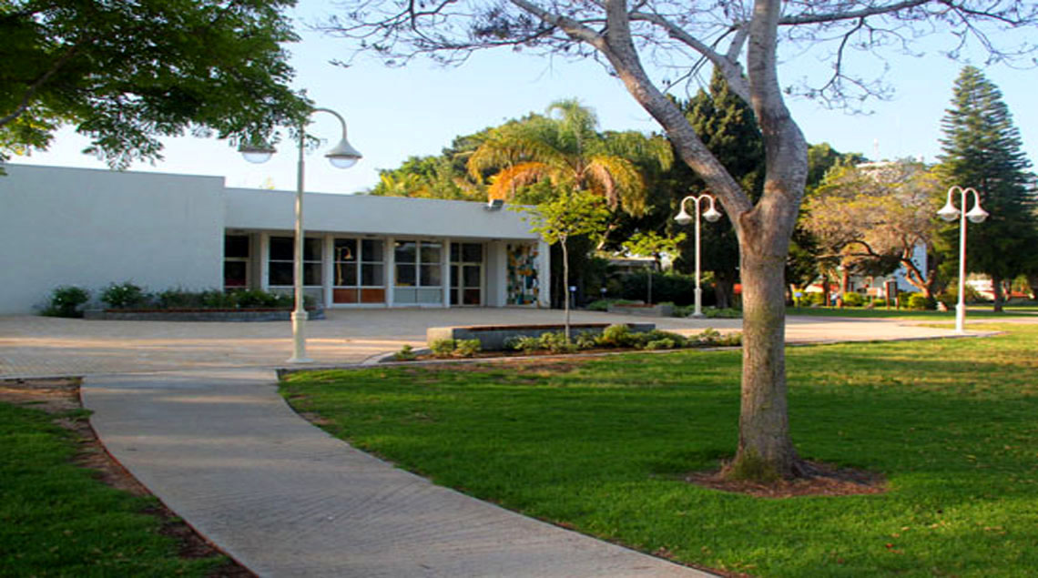 שביל בטון בתוך מדשאה גדולה המוביל לרחבת חדר האוכל.