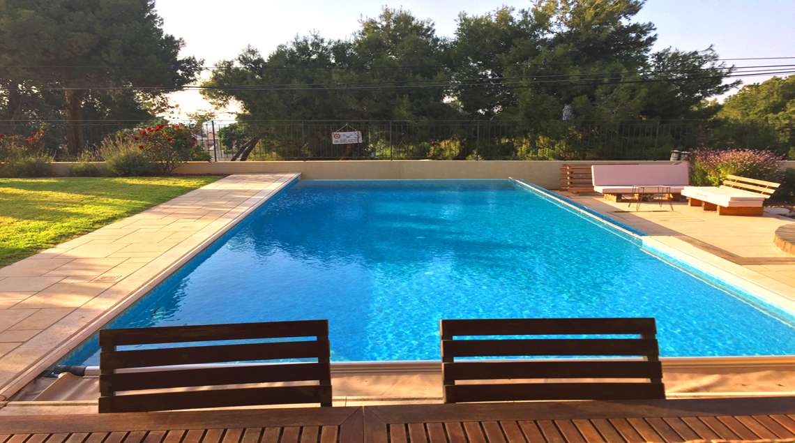 בריכת שחייה וברקע חורשת אורנים.