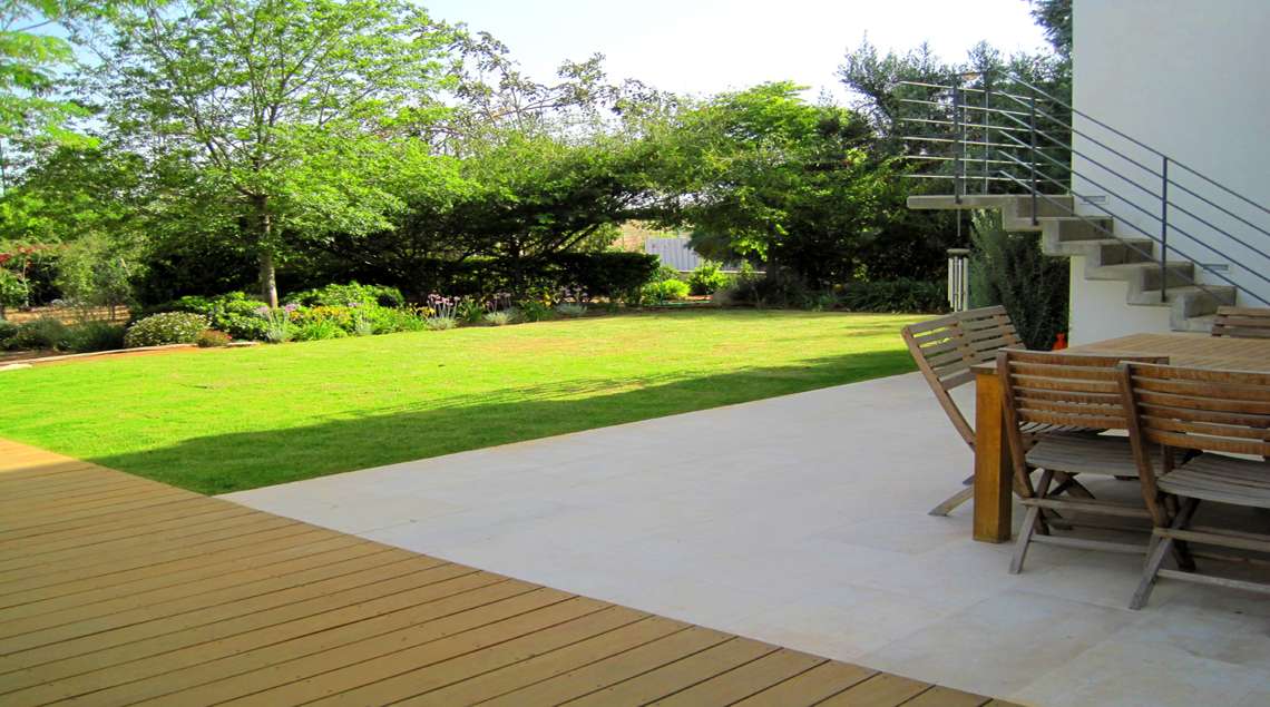 משטח ישיבה מבטון מוחלק נושק לדק עץ ולדשא.