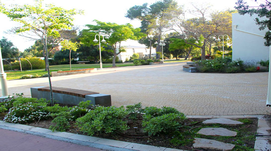 ספסלים עשויים בטון ועץ סביב הערוגות.