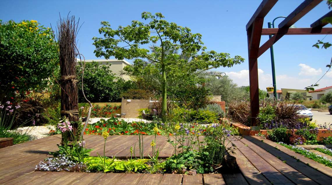 דק עף במפלסים שונים ובתוכו ערוגות פורחות.