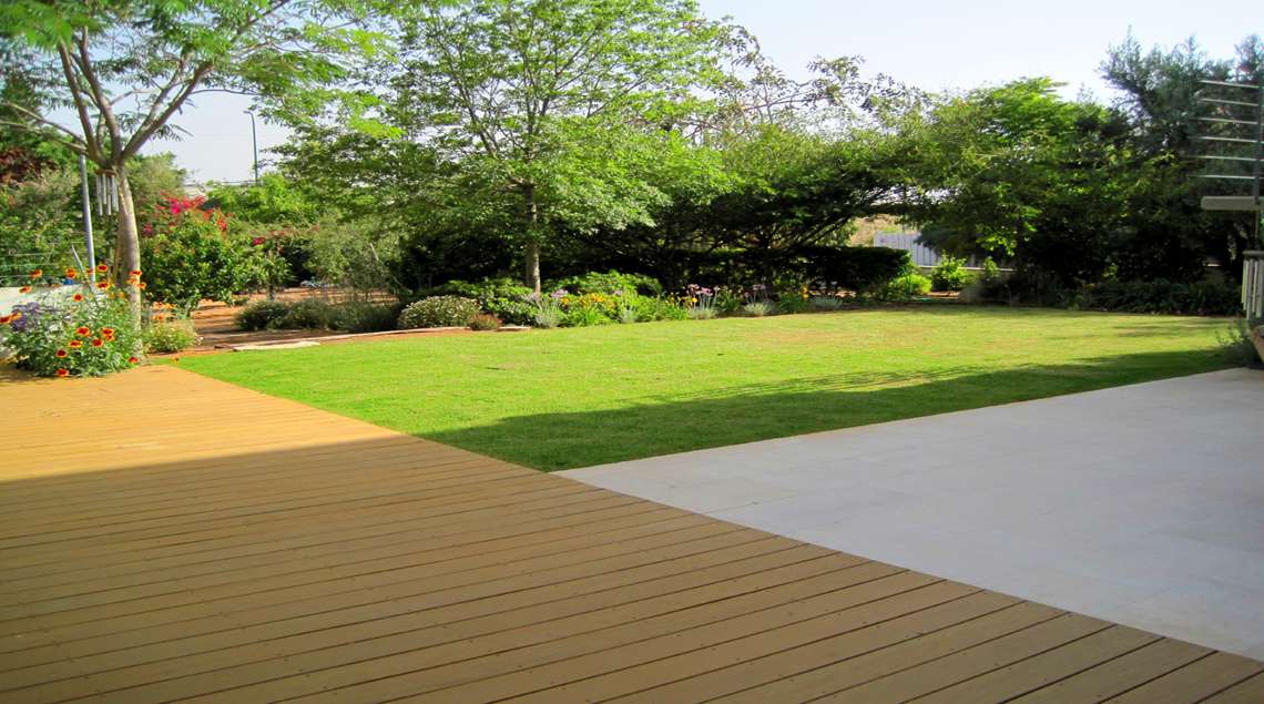 משטח ישיבה מבטון מוחלק נושק לדק עץ ולדשא.