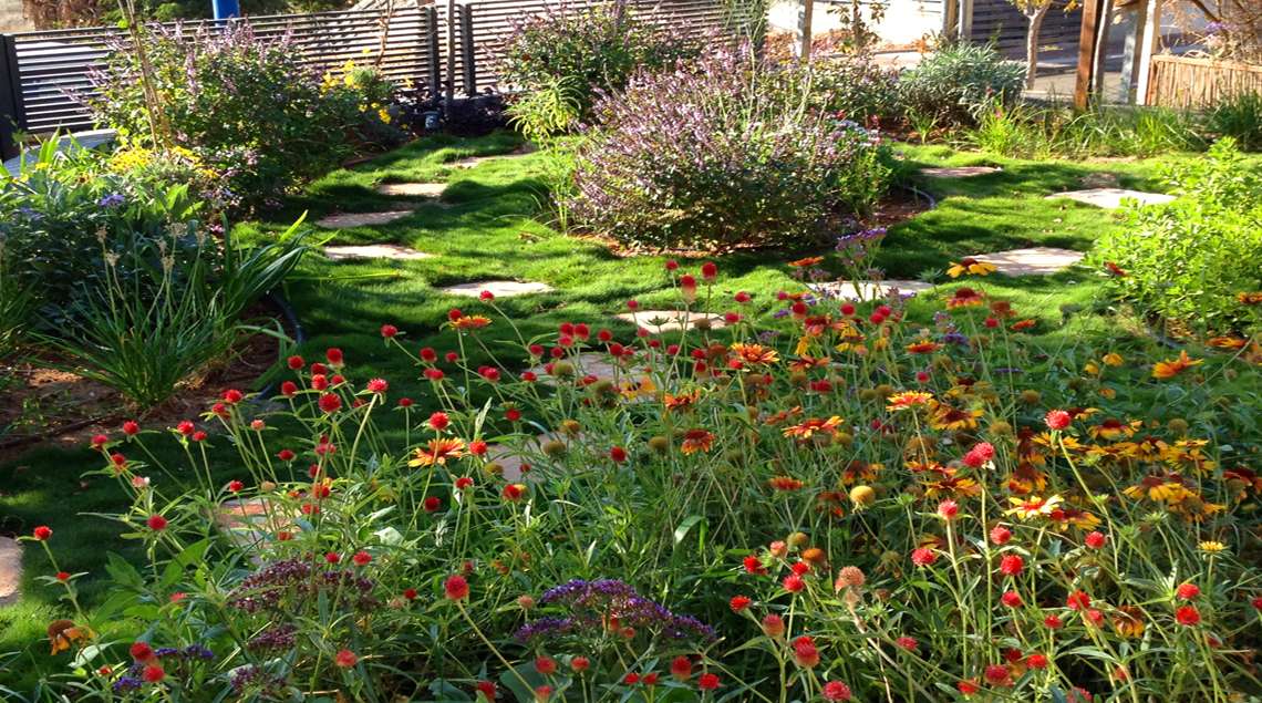 דשא גבעות ובתוכו ערוגות פורחות בכתום, צהוב וסגול.