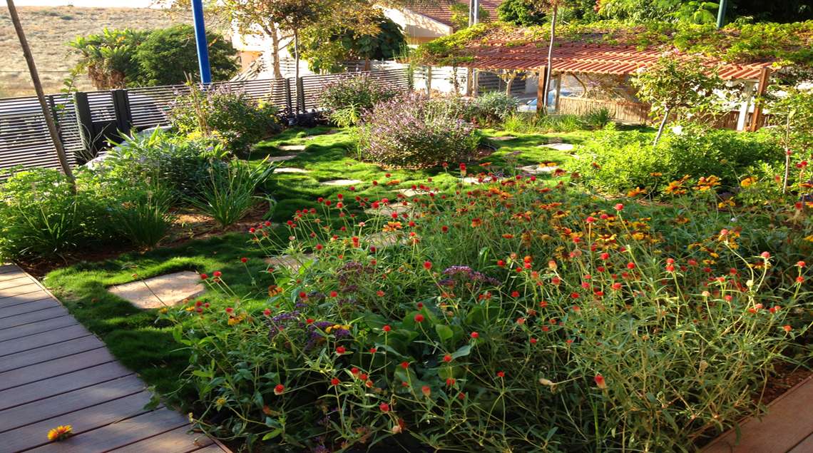 דשא גבעות ובתוכו ערוגות פורחות בכתום, צהוב וסגול.